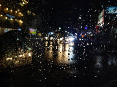 Yağmur mevsiminde yağmurlu bir gecede cam bir kadehte makro su damlacıkları.