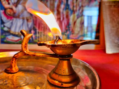 Diya lambasının resmi. Diwali Kutlaması. Çamurdan ya da balçıktan yapılmış yağ lambası ve pamuk fitili. Lit diya lambası. Arka planda Tanrıların ve Tanrıçaların heykeli