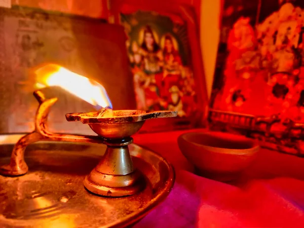 Diya lambasının resmi. Diwali Kutlaması. Çamurdan ya da balçıktan yapılmış yağ lambası ve pamuk fitili. Lit diya lambası. Arka planda Tanrıların ve Tanrıçaların heykeli