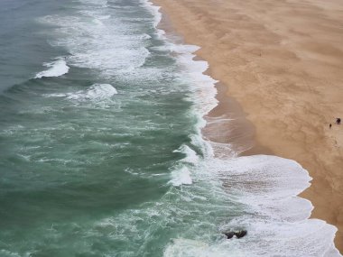 Panoramic view of gigantic powerful foamy waves in North Beach of Nazar or Silver Coast. Popular surf route in Europe, Portugal. Stormy Atlantic ocean.