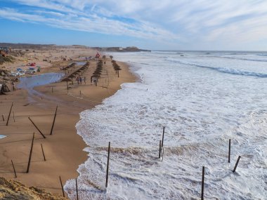 Flooded Guincho beach and stormy Atlantic ocean with white foamy waves. Beautiful landscape in Sintra-Cascais natural park is a reserve on the Portuguese Riviera. Cascais, Portugal.