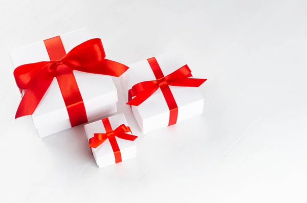 白色礼品盒大小不同 红色缎带和蝴蝶结在白色桌面上 复制空间 小册子 封面设计 传单设计的节日背景 — 图库照片
