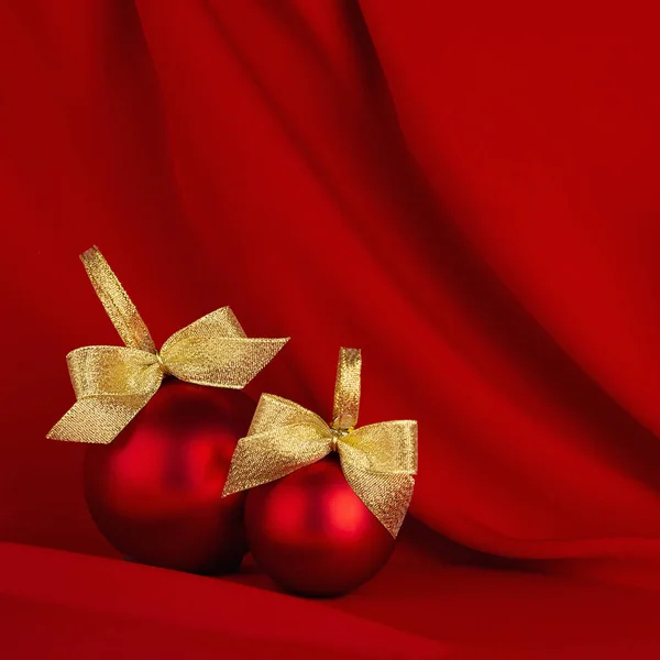 新年背景 风格华丽 有两个发亮的红色球 金色的蝴蝶结在流动的深红色丝绸面料上 正方形 小册子设计的圣诞背景 — 图库照片