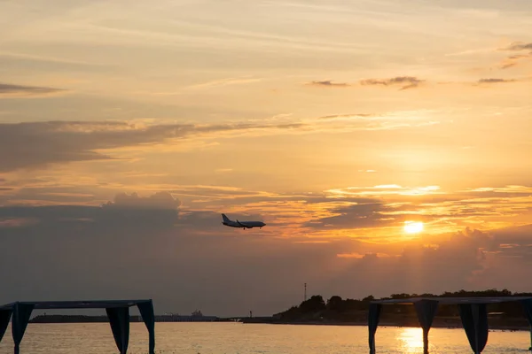 Egy Repülőgép Sziluettje Tenger Strand Hegyek Felhős Lenyugvó Nap Hátterében — Stock Fotó
