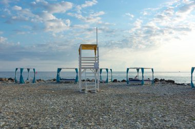 Akşamüstü çakıl taşı kumsalında beyaz tahta kuleyi kurtarın, kumsal ıssız..