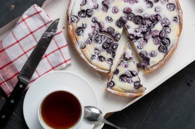 Pudra şekeri, çay bıçağı ve peçete serpiştirilmiş yaban mersinli turta. Tatil konsepti misafirlerin buluşmasıdır. düz yat.