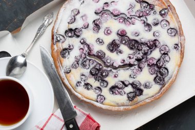 Pudra şekeri, çay bıçağı ve peçete serpiştirilmiş yaban mersinli turta. Tatil konsepti misafirlerin buluşmasıdır. düz yat.