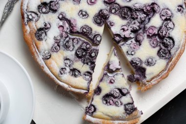 Pudra şekeri, çay bıçağı ve peçete serpiştirilmiş yaban mersinli turta. Tatil konsepti misafirlerin buluşmasıdır. düz yat.