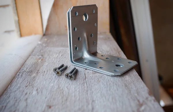 Metal bir köşe ve vidalar inşaat halindeki bir evin pencere eşiğinde yatıyor.,
