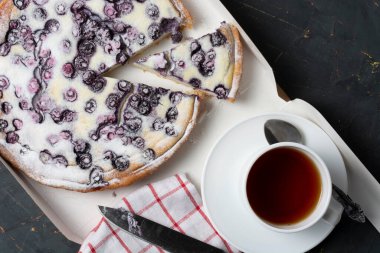 Pudra şekeri, çay bıçağı ve peçete serpiştirilmiş yaban mersinli turta. Tatil konsepti misafirlerin buluşmasıdır..