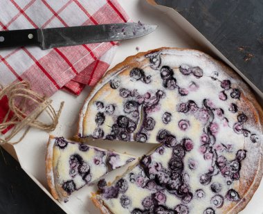 pudra şekeri, bıçak ve peçete serpiştirilmiş yabanmersinli turta. Tatil konsepti misafirlerin buluşmasıdır..