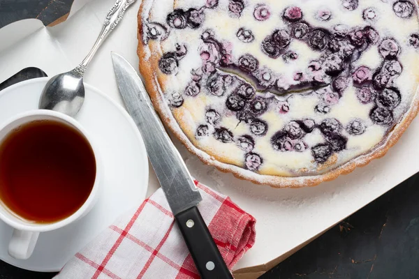 blueberry pie sprinkled with powdered sugar, a tea knife and a napkin. the concept of the holiday is a meeting of guests. flat lay.