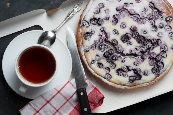 blueberry pie sprinkled with powdered sugar, a tea knife and a napkin. the concept of the holiday is a meeting of guests. flat lay.