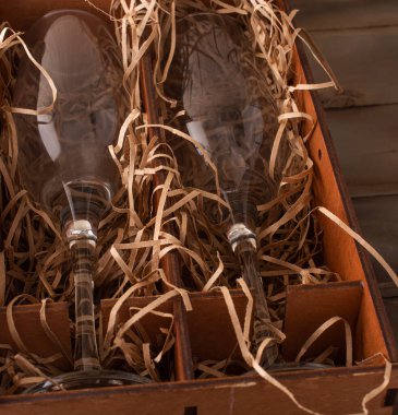 Yumuşaklık için talaşı olan ahşap bir hediye kutusunda iki şampanya kadehi. tatil konsepti. Yakın çekim