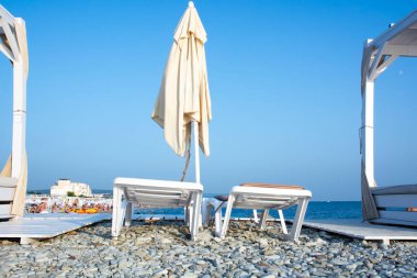 Sabahın erken saatlerinde deniz ve mavi gökyüzünün arka planına karşı beyaz katlanmış perdeleri olan boş kabinler. Deniz kenarında tatil kavramı. Kopyalamak için boşluk.