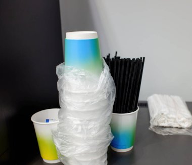 Çay ve kahve için renkli fincanlar yığını. Kokteyl tüpleri ve kahve makinesinin yanında. yakın plan.