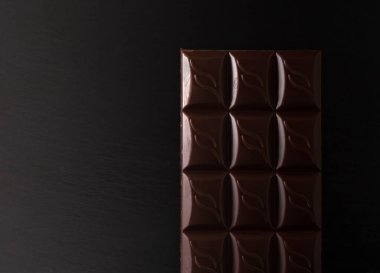 chocolate bar on a black flat stone in low light. copy space. flatlay.