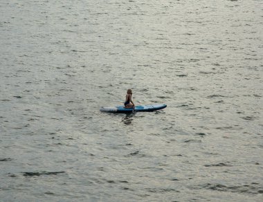 Sup tahtasındaki yalnız bir kız denize doğru yüzdü. Turizm ve seyahat