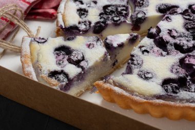 Bir parça yaban mersinli turta üzerine pudra şekeri serpiştirilmiş.