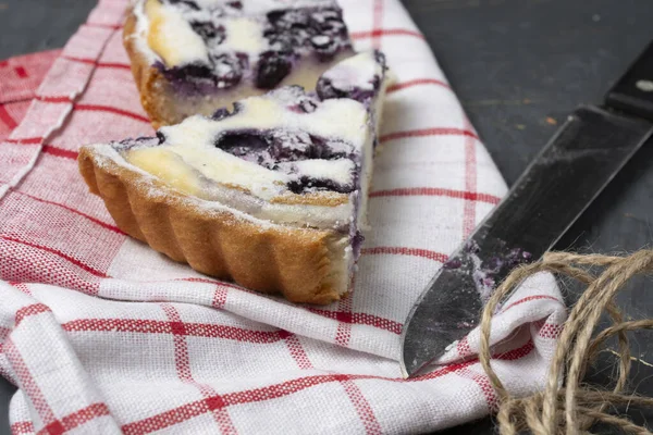 Yakın plan bir parça yaban mersinli turta üzerine pudra şekeri serpiştirilmiş ve yanında da mutfak bıçağı.