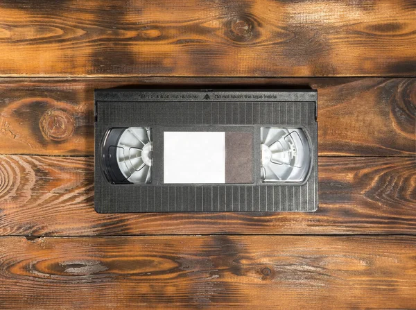 Ahşap arka planda siyah bir video kaset. Boşluğu kopyala.