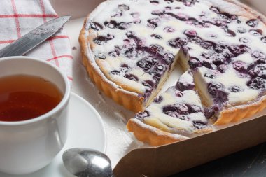 Pudra şekeri, çay bıçağı ve peçete serpiştirilmiş yaban mersinli turta. Bayram ve Şükran Günü konsepti.