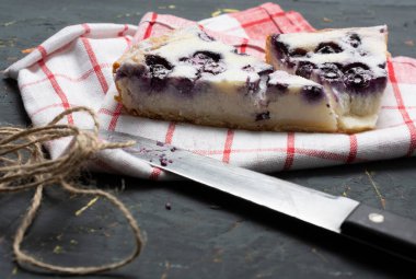 Yakın plan, üzerine pudra şekeri serpiştirilmiş yabanmersinli turta ve yanında uzanan mutfak bıçağı, doğum günü pastası, aile yemeği ve Noel konsepti..