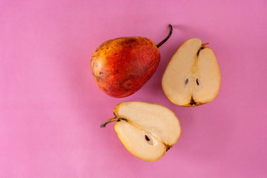 İki armut, biri pembe arka planda ikiye bölünmüş. Boşluğu kopyala.