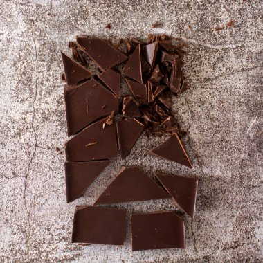 Beton bir arka planda kırılmış siyah çikolata çubuğu. Düz çizgi ve boşluk kopyala.