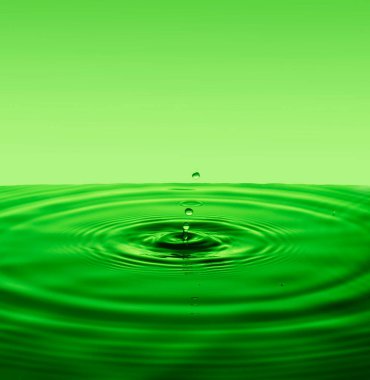 Yüzey suyuna düşen damladan farklı çemberlere sahip yeşil bir arka plan. Boşluğu kopyala.