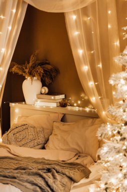 Noel kahverengi oda iç tasarımında sihirli sıcak ve rahat bir akşam, Xmas ağacı süslemeli ışıklar çelenkler tatil oturma odası. Kanepe kemerli kanepe aynası yeni yıl tatili tarzı.