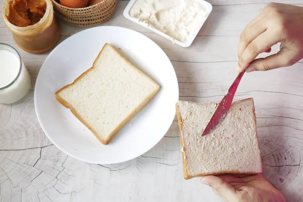 Masadaki ekmeğe sürülmüş peynir kremi.