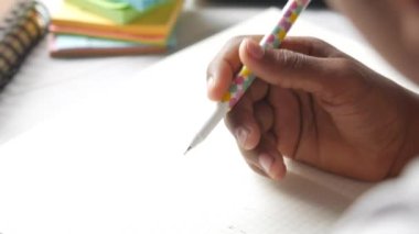 Not defterine el yazısı yazan kız çocuğunun kenar görünümü.