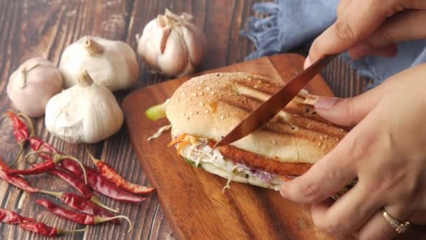 Сэндвич женской ручной резки на деревянном столе — стоковое видео