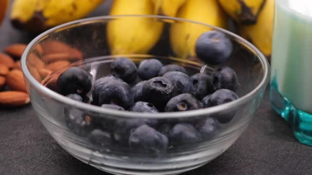 Gocce di bacca azzurra fresca in ciotola con banana, latte e mandorla sul tavolo — Video Stock