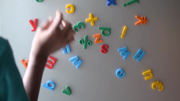 Barn pojke organisera färgglada plast bokstäver på ett kylskåp — Stockvideo