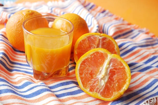 El jugo de naranja en el cristal sobre el fondo de color — Foto de Stock
