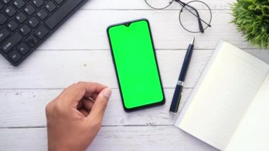 Ofis masasında akıllı telefon kullanan bir adamın üst görüntüsü. 