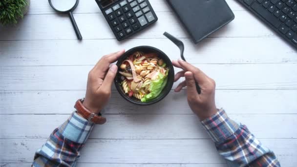 Hombres comiendo ensalada de verduras frescas en tazón en el escritorio de la oficina — Vídeos de Stock