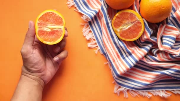 사람 이손으로 오렌지 색 배경에 오렌지 열매 조각을 들고 있는 모습 — 비디오