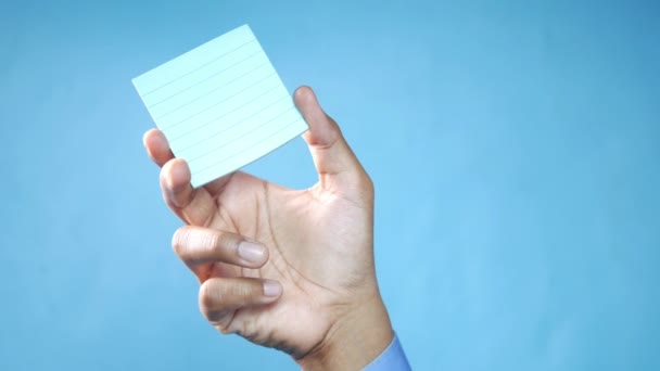 Man hand hold a sticky note against blue background — Stock Video