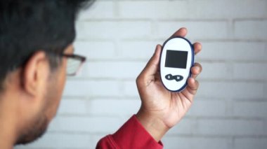 Glikoz ölçer tutan genç adamlar 