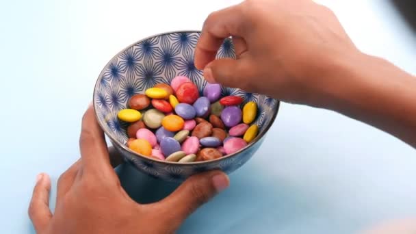 Мальчик собирает разноцветные сладкие конфеты в миске крупным планом — стоковое видео