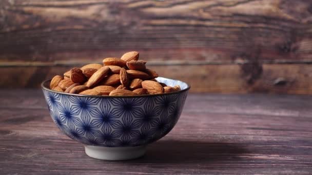 Hand pick a bowl of almond nut on table — Stock Video