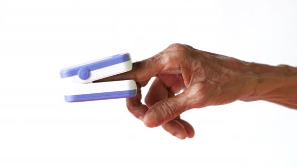 Senior jonge vrouwen hand met behulp van pulsoximeter tegen witte achtergrond — Stockvideo