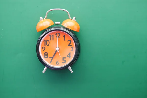 Reloj despertador viejo naranja sobre fondo verde —  Fotos de Stock