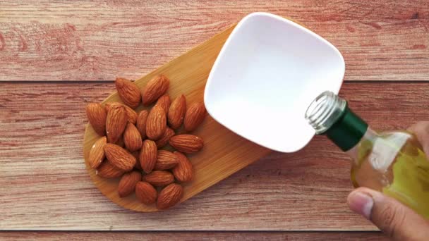 Kacang almond dan minyak menuangkan dalam wadah di atas meja — Stok Video