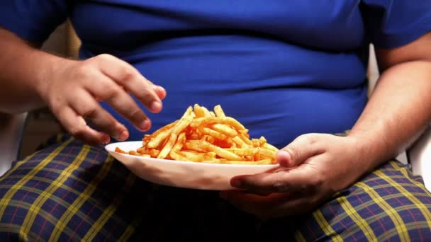 Un hombre gordo comiendo papas fritas mientras se encuentra — Vídeos de Stock