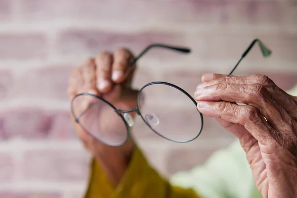 高年级女子手拿着旧眼镜的特写镜头 — 图库照片