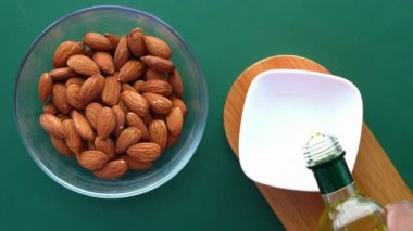 Kavanozdaki badem manzarası ve kabın içine dökülen yağ. 